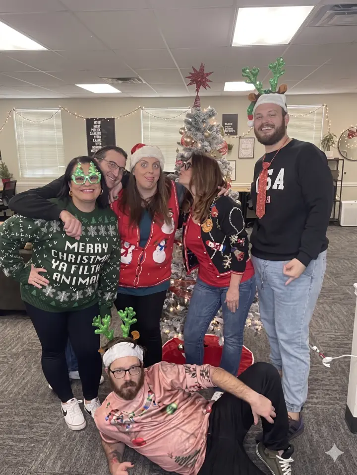 The Benefits Boss team in ugly Christmas sweaters at the office holiday party