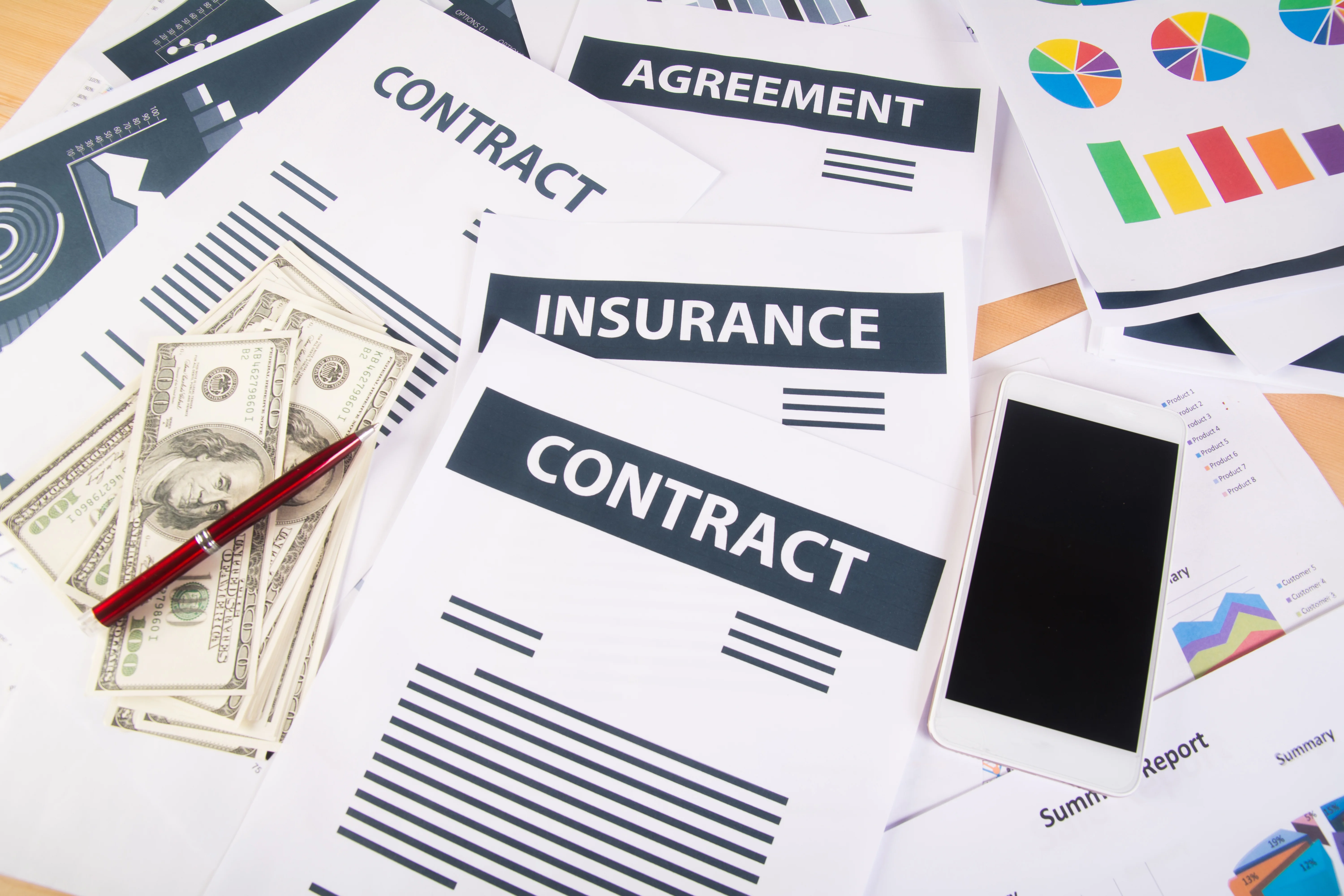 close up of insurance papers with phones and graphs on table