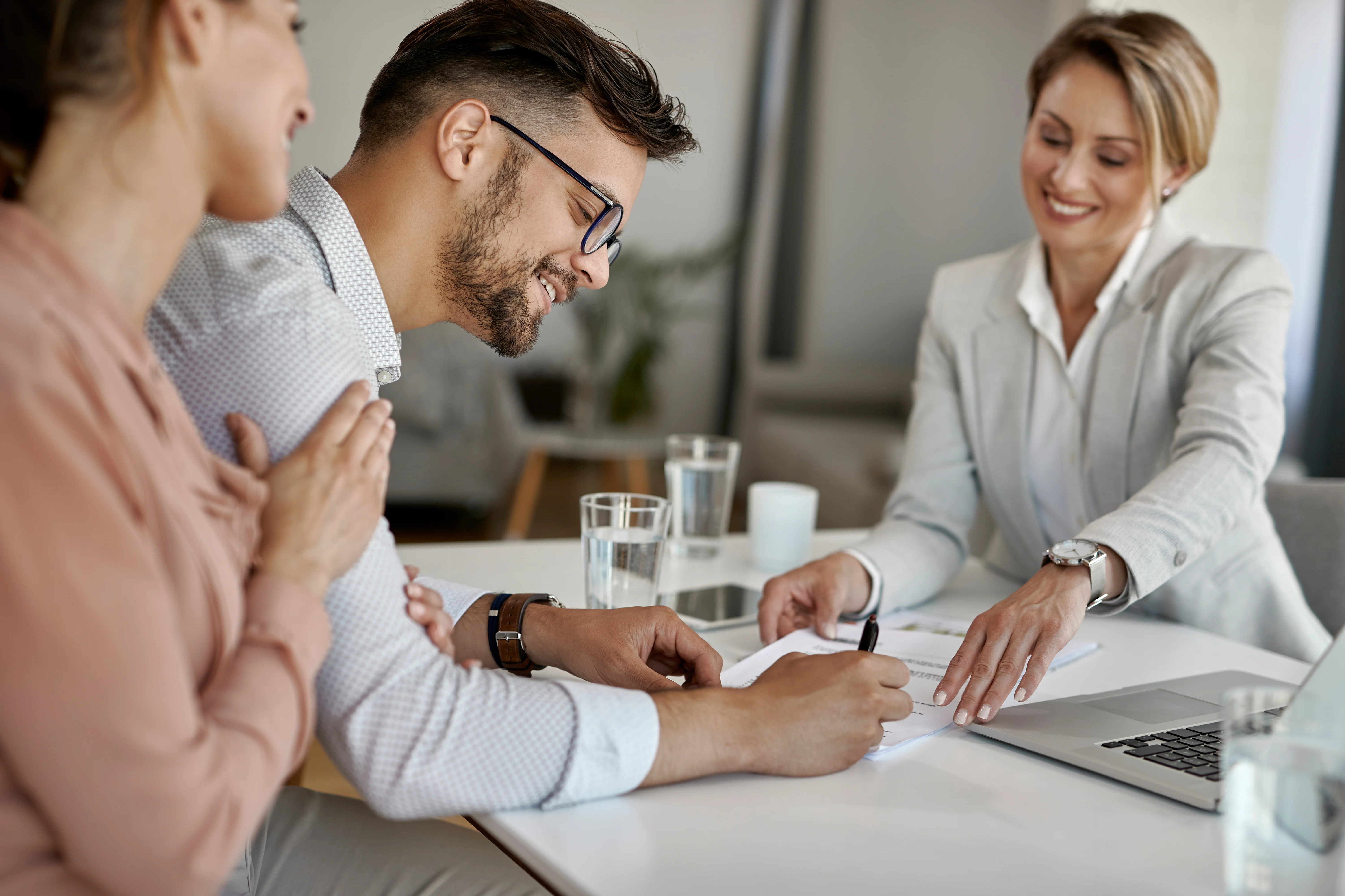 Couple signing health insurance paperwork with an advisor