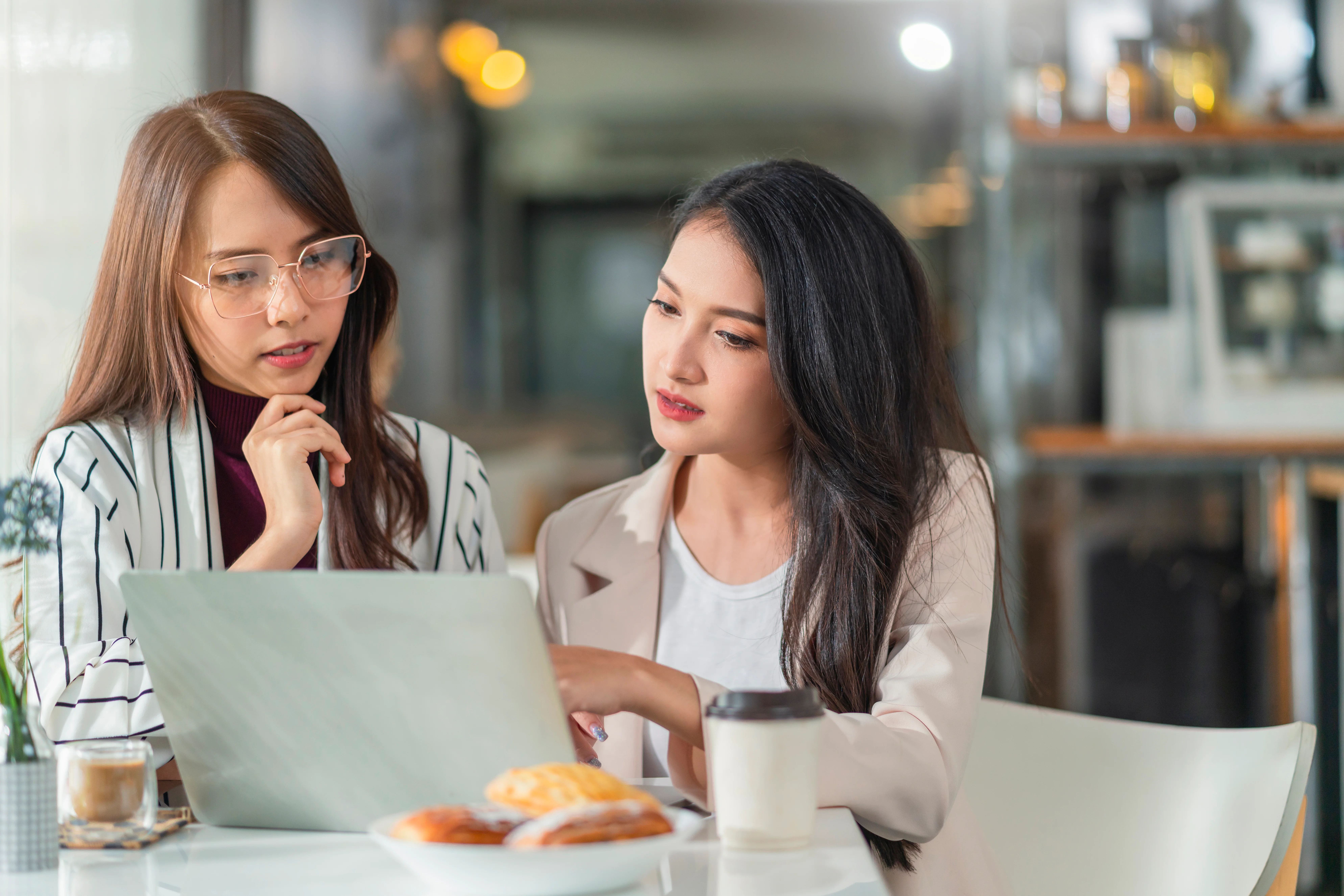Two women reviewing health insurance options together on a laptop
